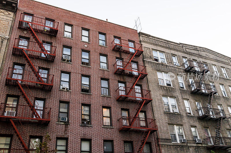 砖砌公寓共管大楼外部建筑Fordham Heights中心，布朗克斯，纽约市，曼哈顿，纽约市，有消防通道，窗户，空调在晚上